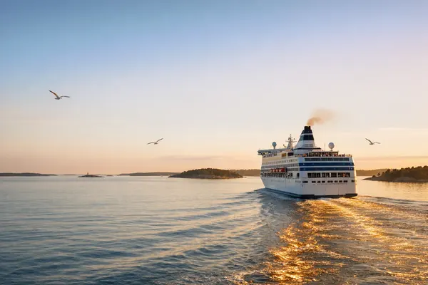 Cruiseskip på vei ut gjennom skjærgården i kveldssol
